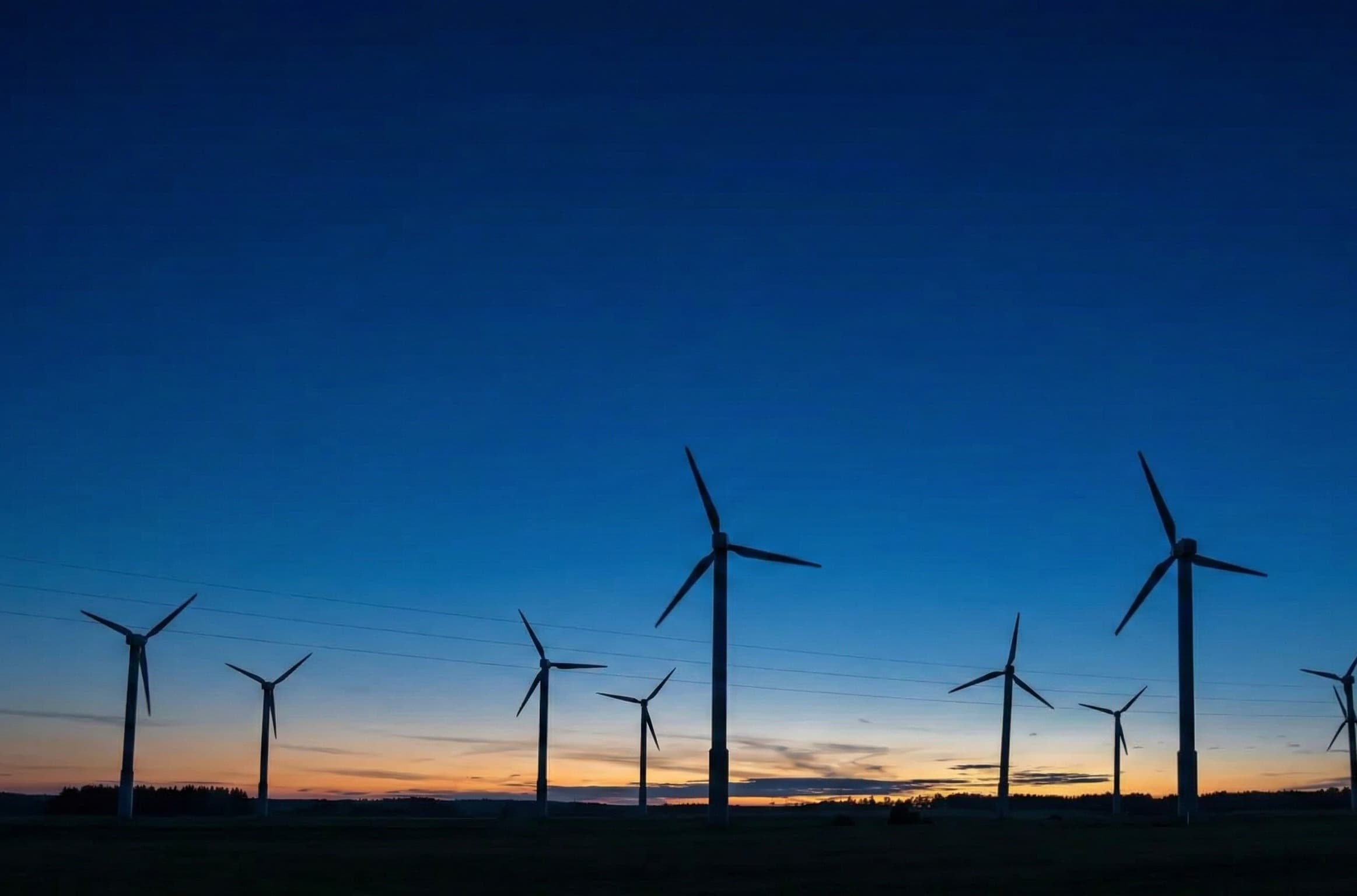 Silhouetten von Windrädern vor einem Abendhimmel – KlimaUnion Studie zur Versorgungssicherheit und Dunkelflaute